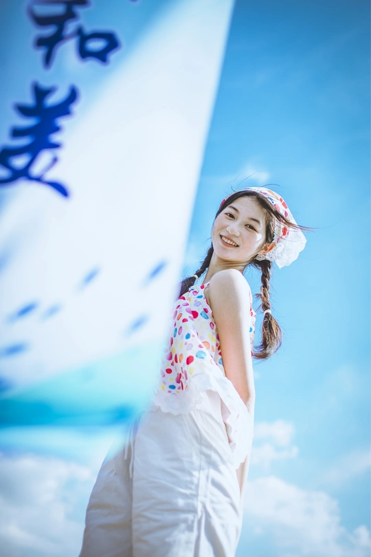 一位穿着连衣裙的年轻女孩站在蓝天之下