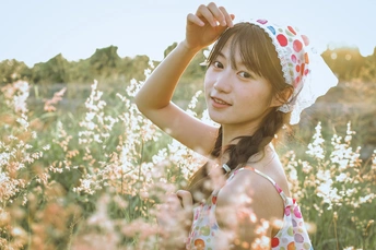 一个小女孩戴着帽子站在一个田野里