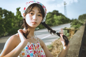 一个小女孩站在路边 双手插在头发里