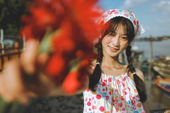 站在船前的年轻女子手持红花