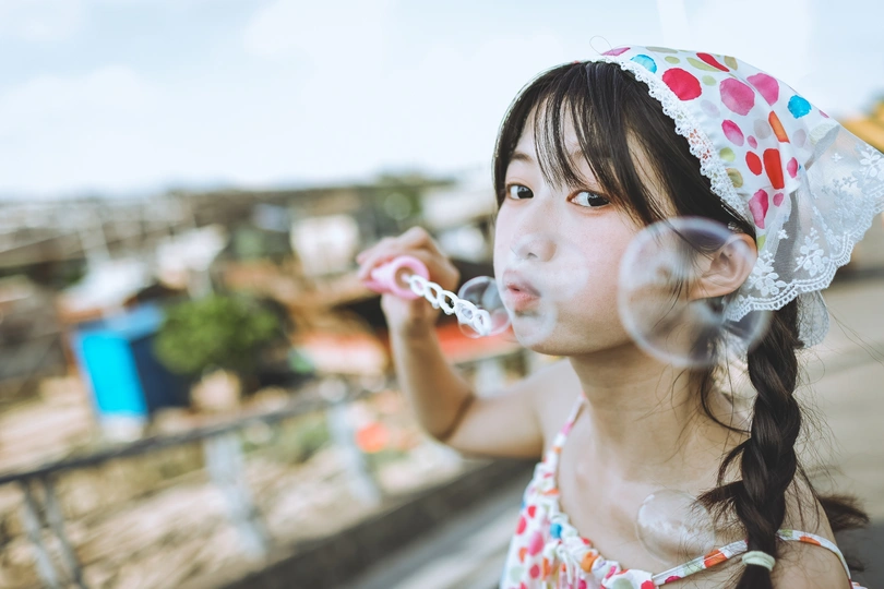 一个小女孩在户外吹泡泡。