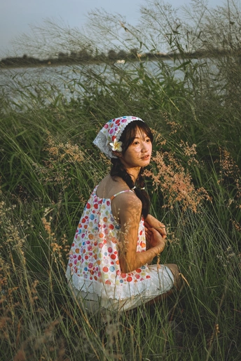 一个穿着连衣裙的年轻女子坐在一片高草地上