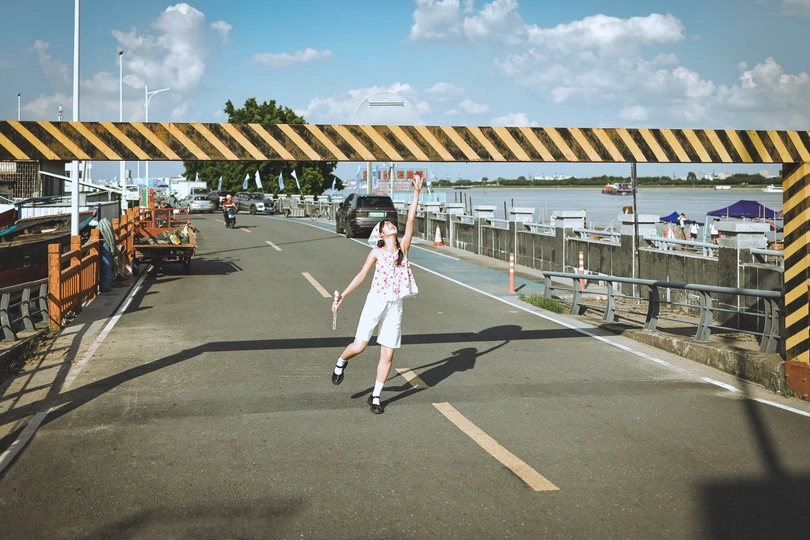 一个小女孩骑着滑板车沿着桥下的街道滑行