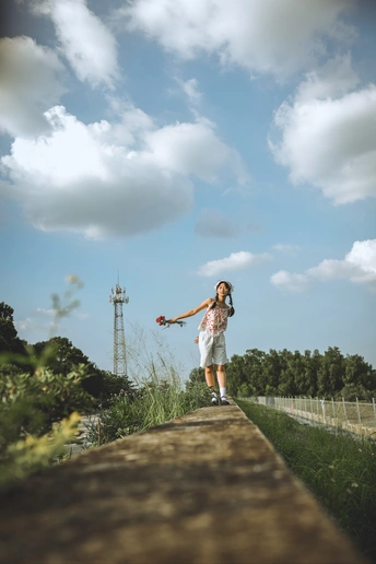 一个穿着连衣裙的小女孩站在一根木桥上 双手伸向天空。