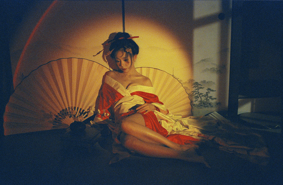 在昏暗的房间里 一个穿着连衣裙的年轻女子坐在床上 撑着一把撑开的伞