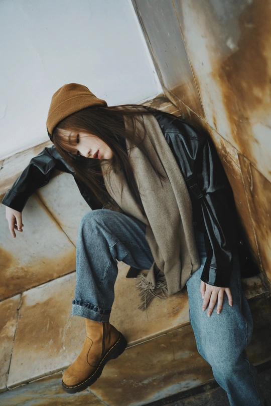 一个戴着帽子、牛仔裤和靴子坐在地板上的年轻女子