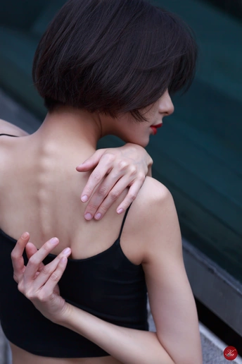 一位年轻女子双手搭在肩上