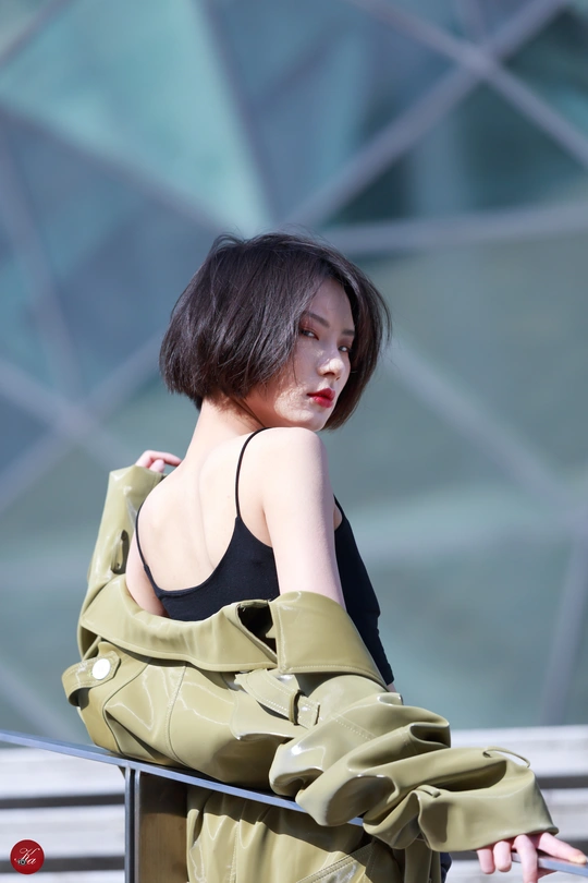 一个穿着绿色连衣裙靠在金属栏杆上的年轻女子