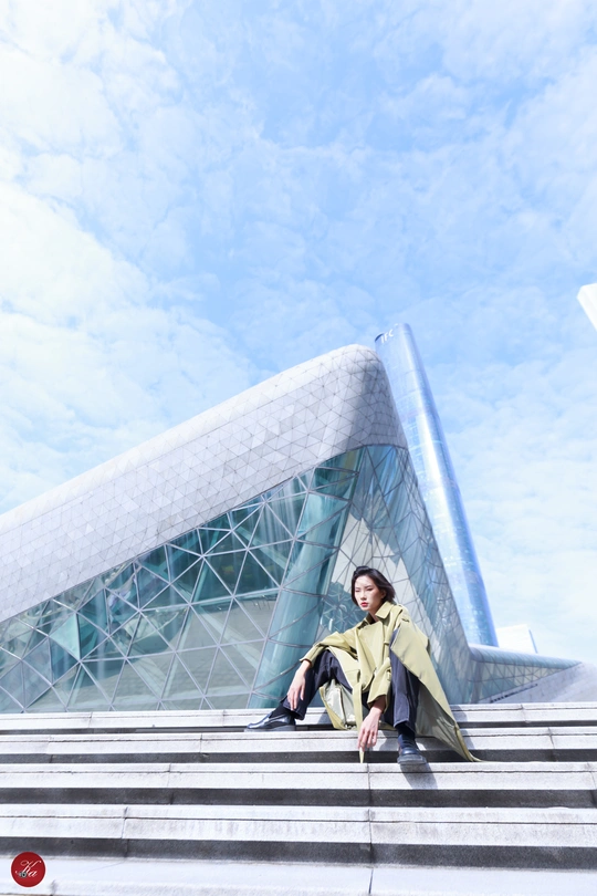 一个穿着黄色外套的女人坐在一栋大楼前的台阶上