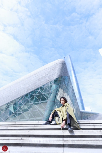 一个穿着黄色外套的女人坐在一栋大楼前的台阶上