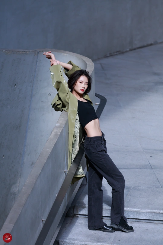 一名身穿黑色夹克和黑色裤子的年轻女子靠在滑板坡道上的墙上