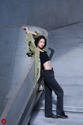 一名身穿黑色夹克和黑色裤子的年轻女子靠在滑板坡道上的墙上