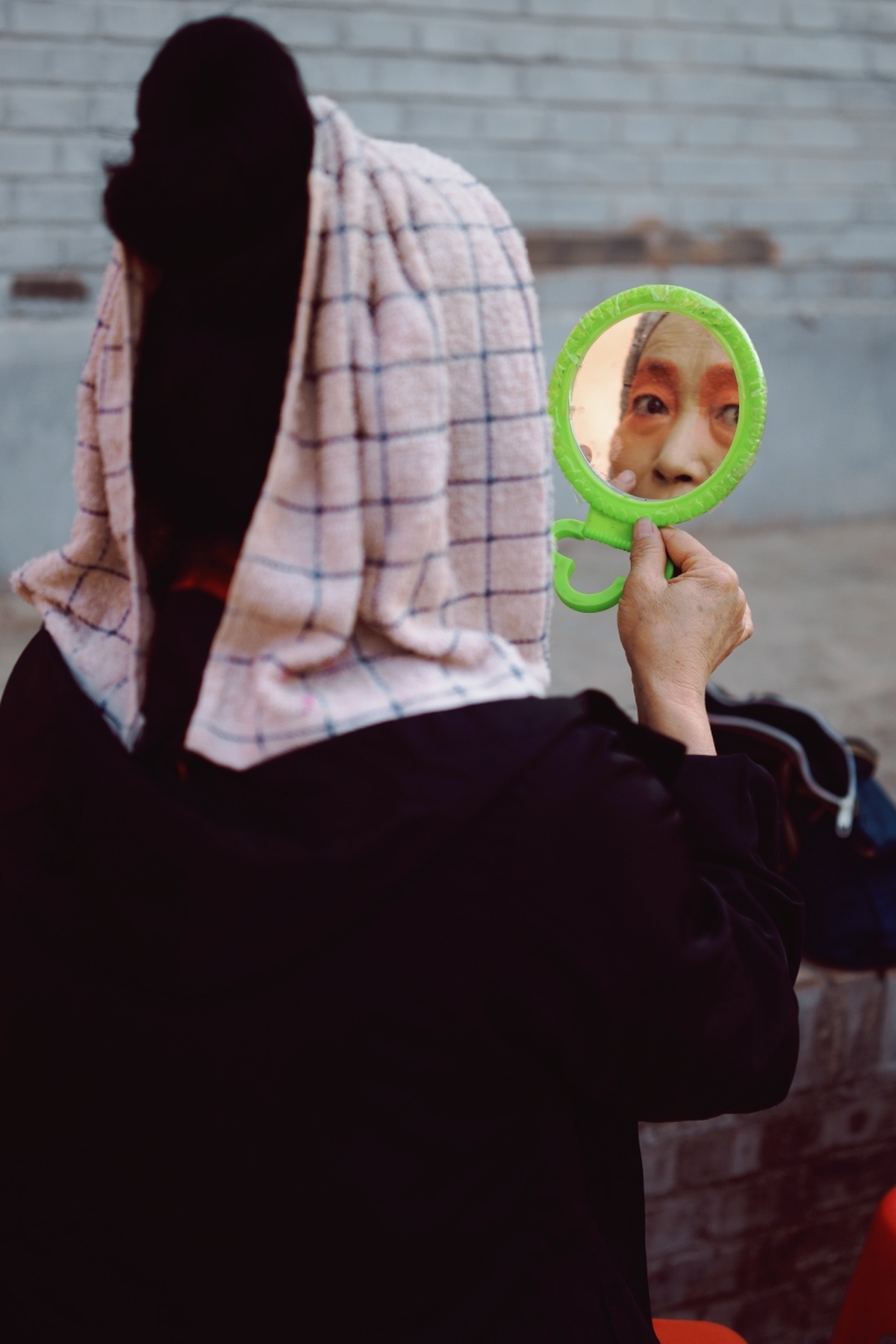 一位年轻女子举着绿色镜子照着她的脸