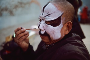 一个戴面具和化妆的男子抽烟。