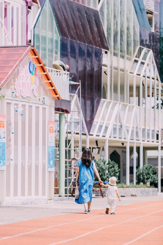 一位年轻女子和一个小女孩手挽手在前面的建筑物前行走