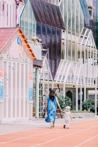 一位年轻女子和一个小女孩手挽手在前面的建筑物前行走