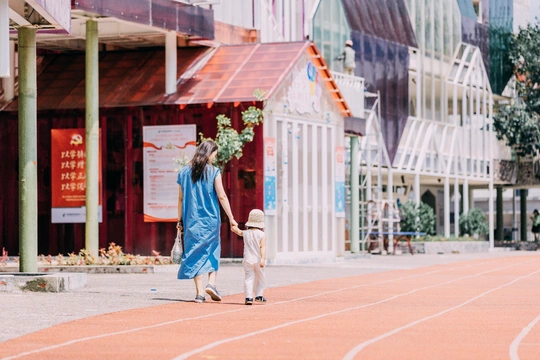 一位妇女和一名儿童手挽手在城市中的跑道上行走