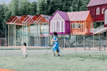 孩子们在公园里踢足球 周围有五颜六色的小屋和草地上一个游乐场。