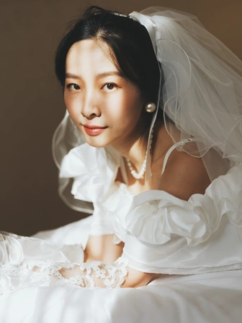 一位年轻女子穿着白色长裙和面纱摆姿势照相