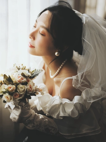 一位女子抱着一束白花 凝视着窗外的肖像