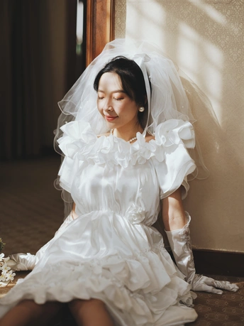 一个穿着白色长裙和面纱的年轻女子坐在蛋糕旁边