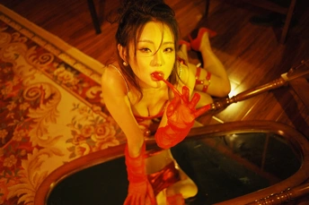 一位穿着红裙子的女人手里拿着刀 站在镜子前和桌子前的蜡烛前摆姿势