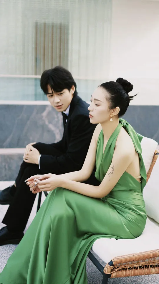 一位穿着绿色连衣裙的女人坐在一位男士旁边