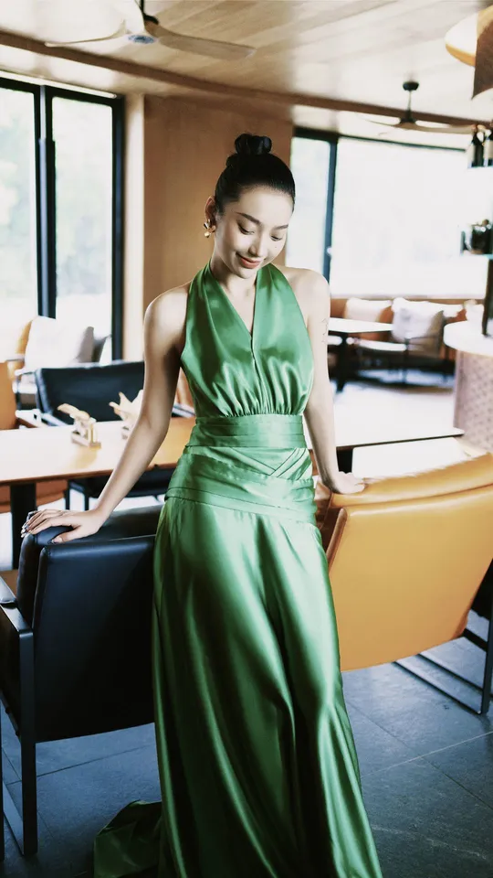 一位穿着绿色长袍的女性站在一个艺术装饰风格的餐厅里