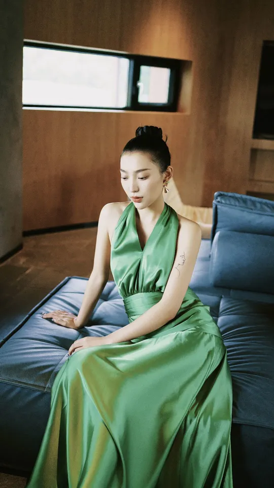 一个穿着绿色连衣裙的美女坐在床上或沙发上