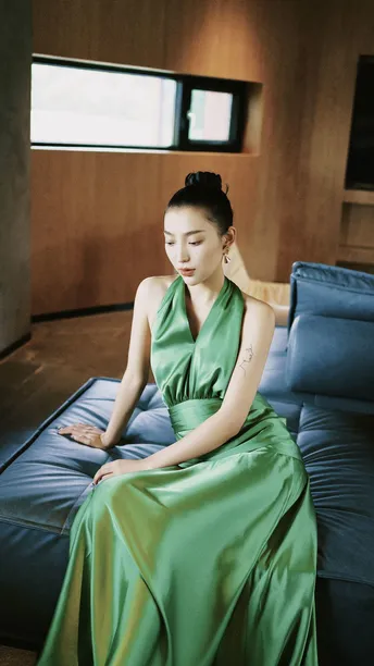 一个穿着绿色连衣裙的美女坐在床上或沙发上