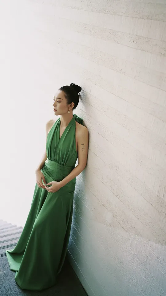 一位穿着绿色连衣裙的模特靠在墙上