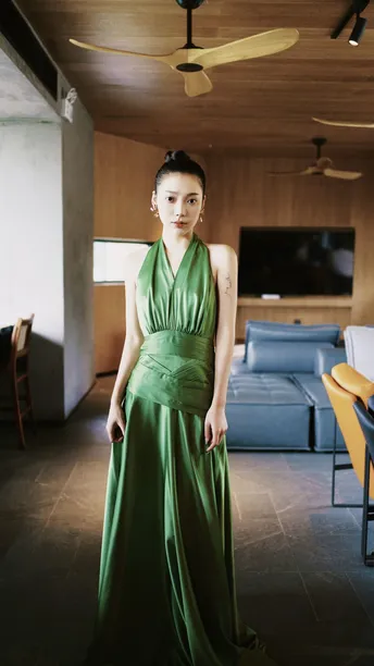 一位穿着绿色连衣裙的女士站在一个开放式概念客厅里