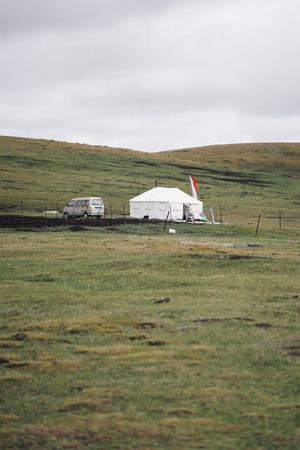 一片绿色的草地 旁边有一顶白色的帐篷 一辆卡车和一辆白色的货车停在路边。