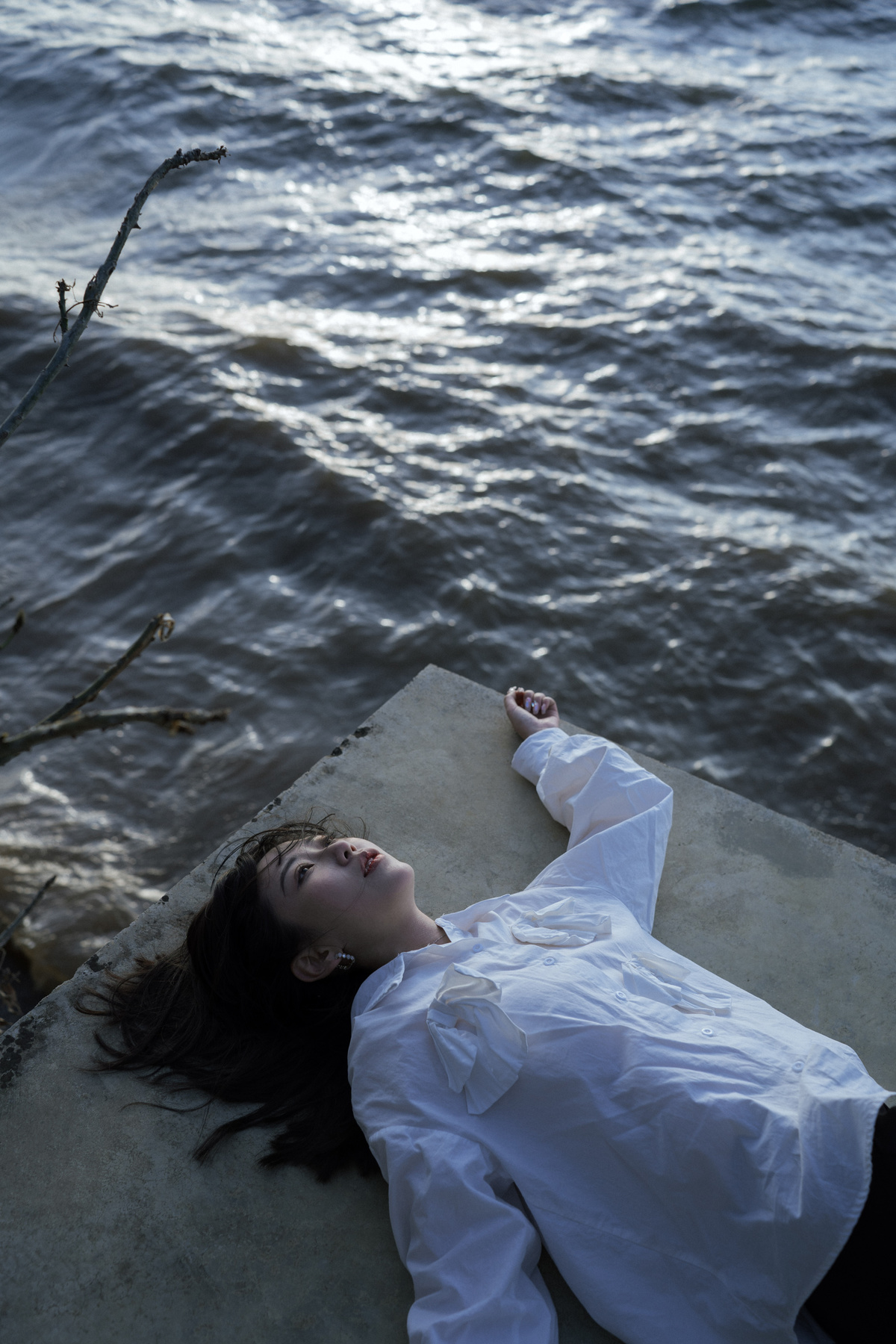 一个穿着白衬衫的年轻女子躺在湖中漂浮的水体上