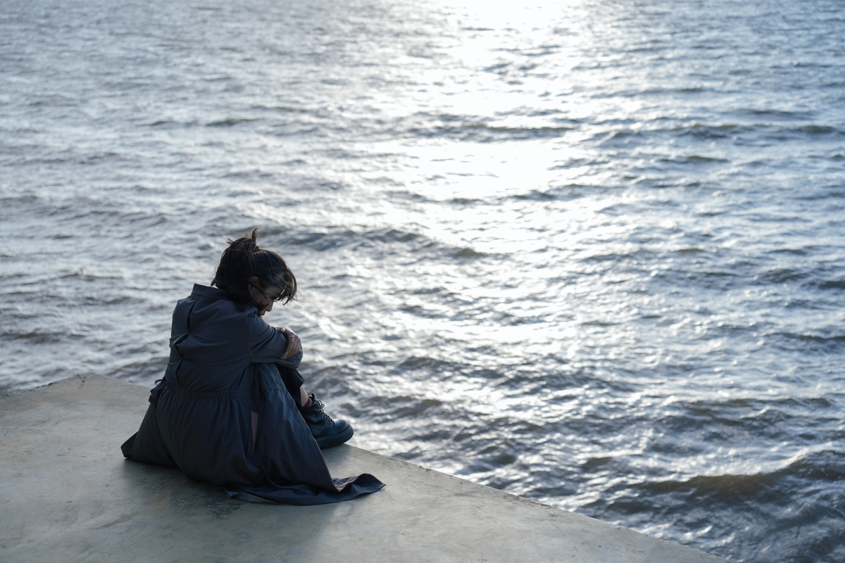 一个年轻的女人坐在海边看着一片水域