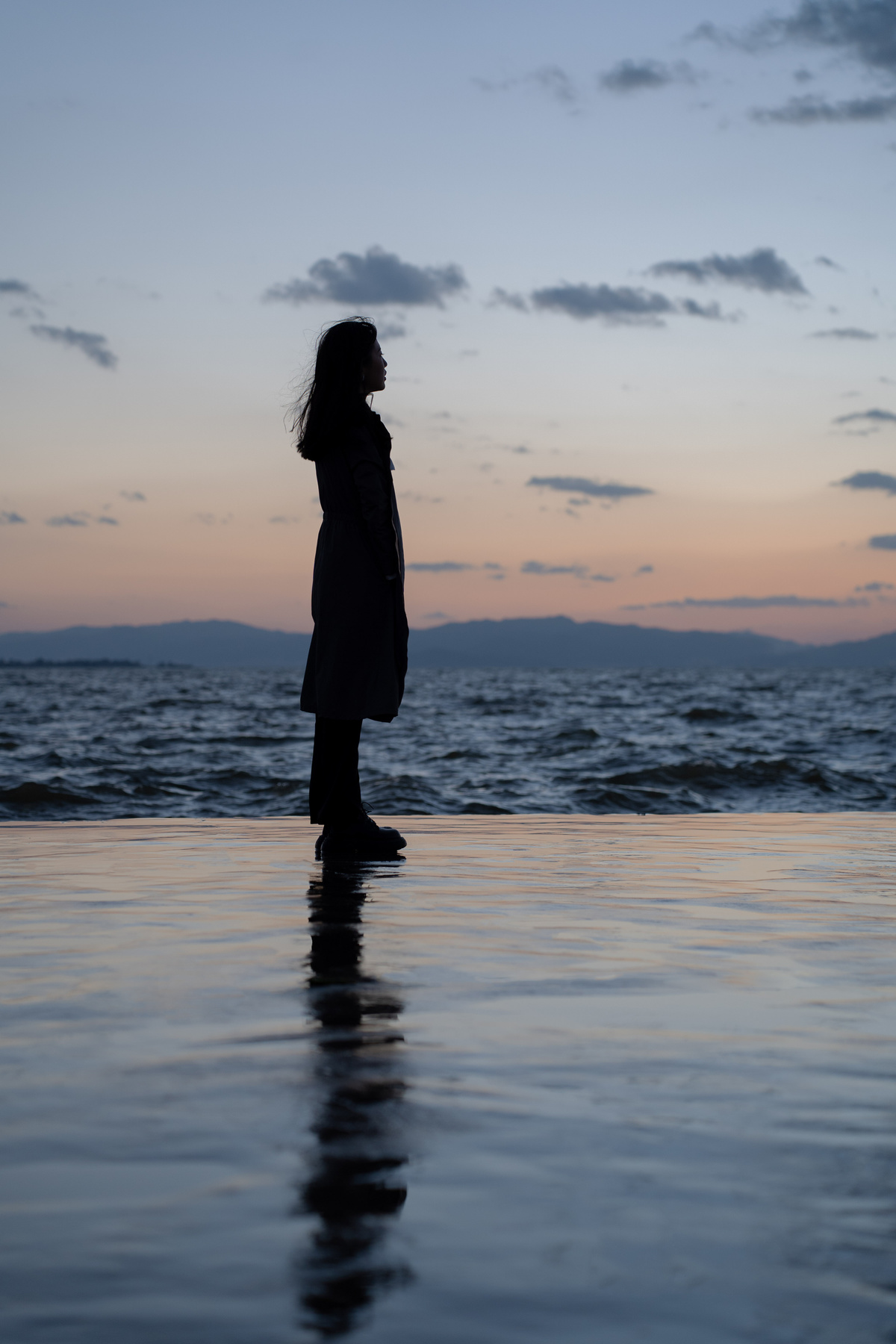 黄昏时分 一名女子站在海滩上的水中俯瞰着一片水域