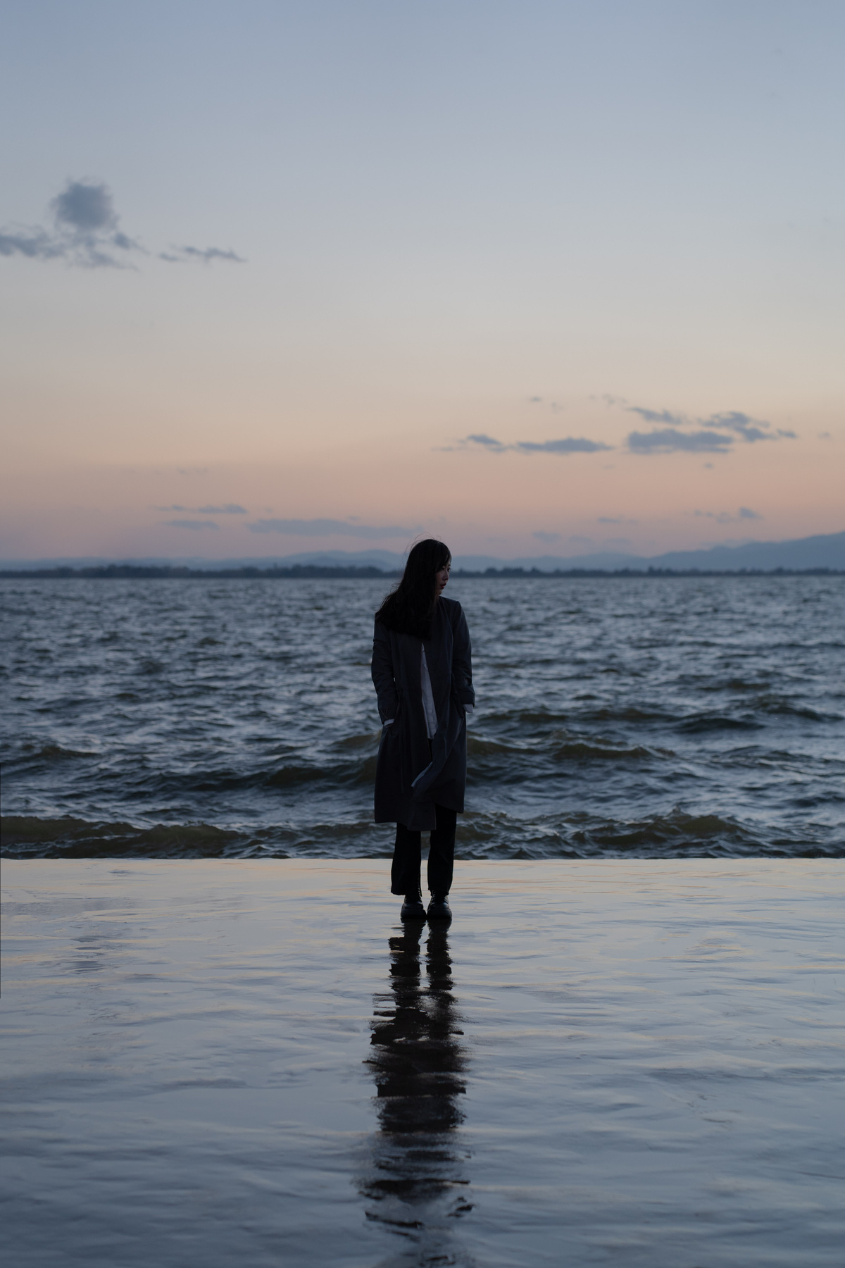 日落时 一个女孩站在海滩的水中