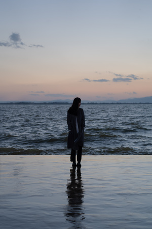 日落时 一个女孩站在海滩的水中