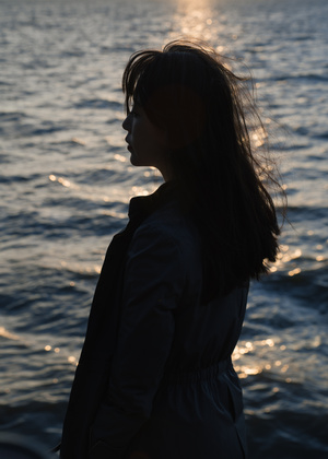 日落时 一位年轻女子站在海滩上眺望着一片水域