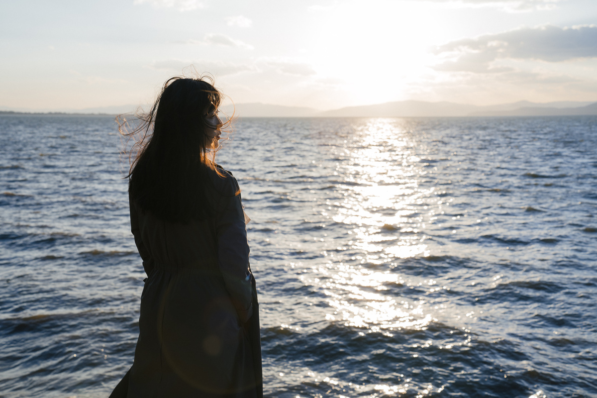 日落时 一位年轻女子站在海滩上眺望着一片水域