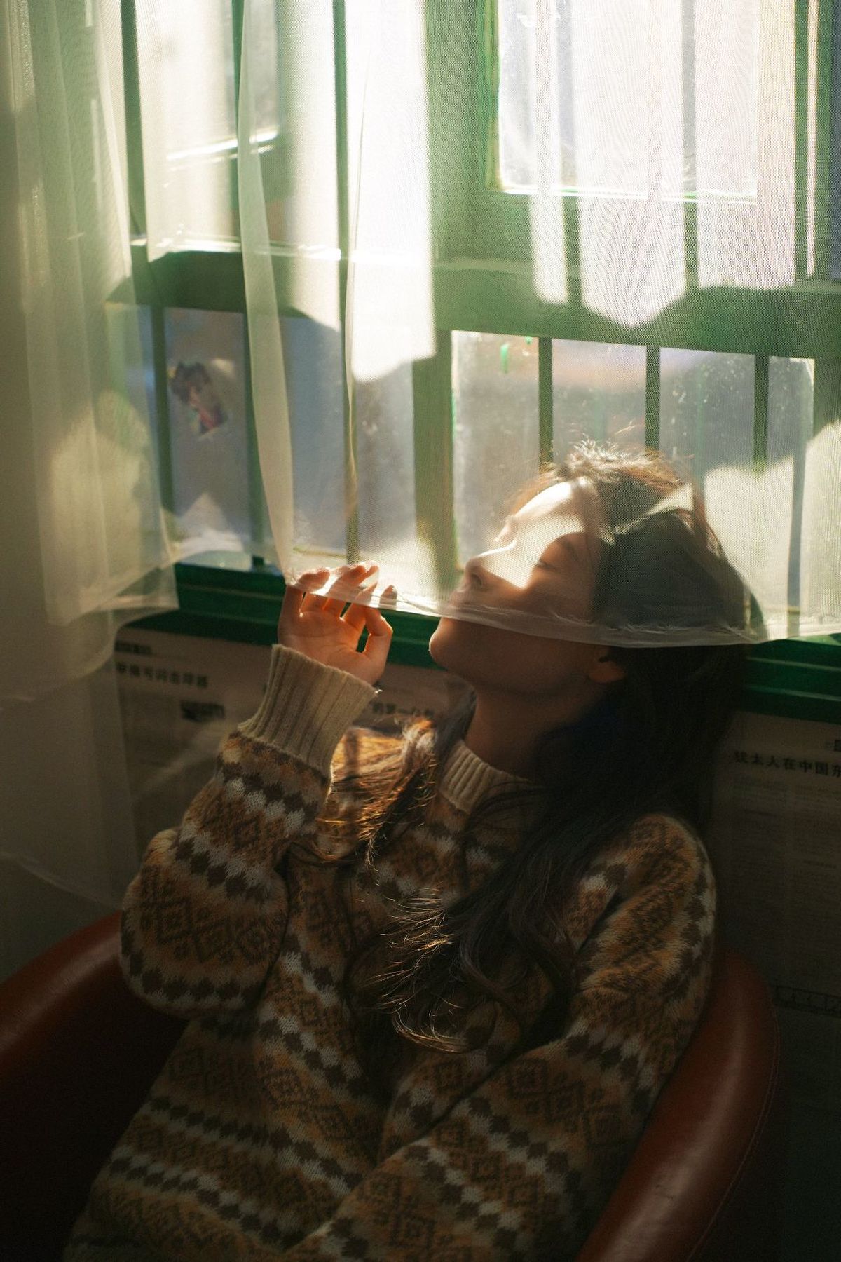 一个年轻女子坐在有窗户的房间里 戴着帽子 坐在椅子上