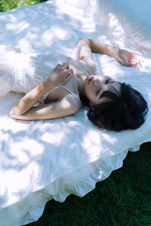 一个年轻女子躺在铺有白色床单和草的床上