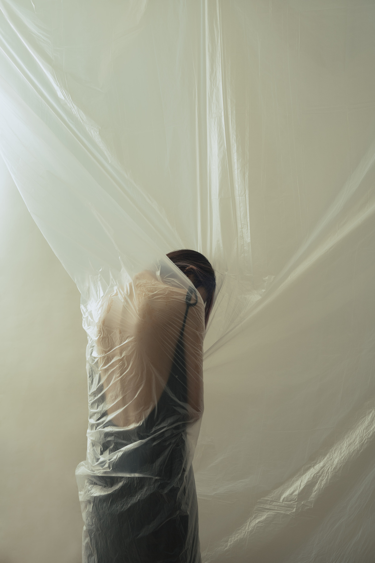 一张女人站在被塑料薄膜覆盖的房间的照片
