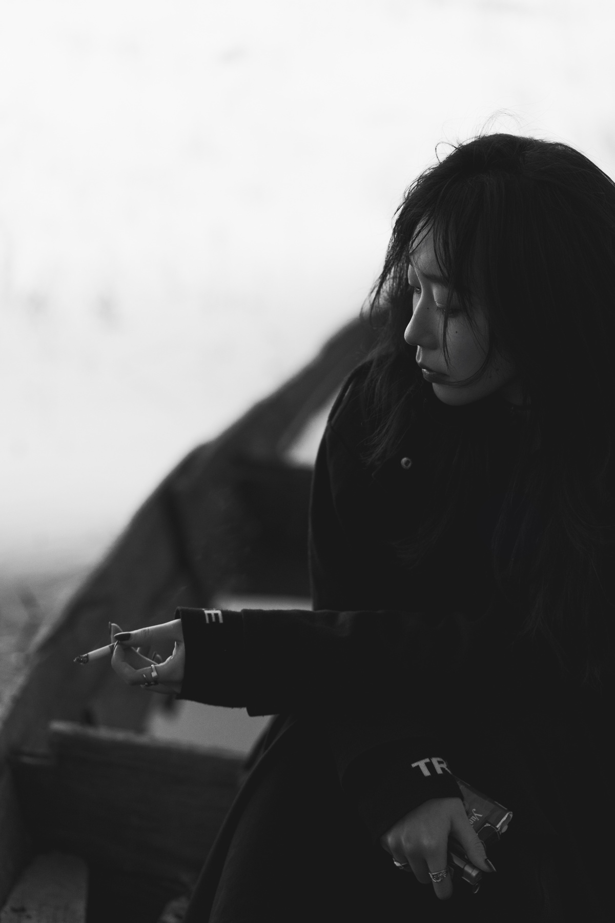 一张黑白照片 一位年轻女子坐在长凳上 手里拿着一支香烟。