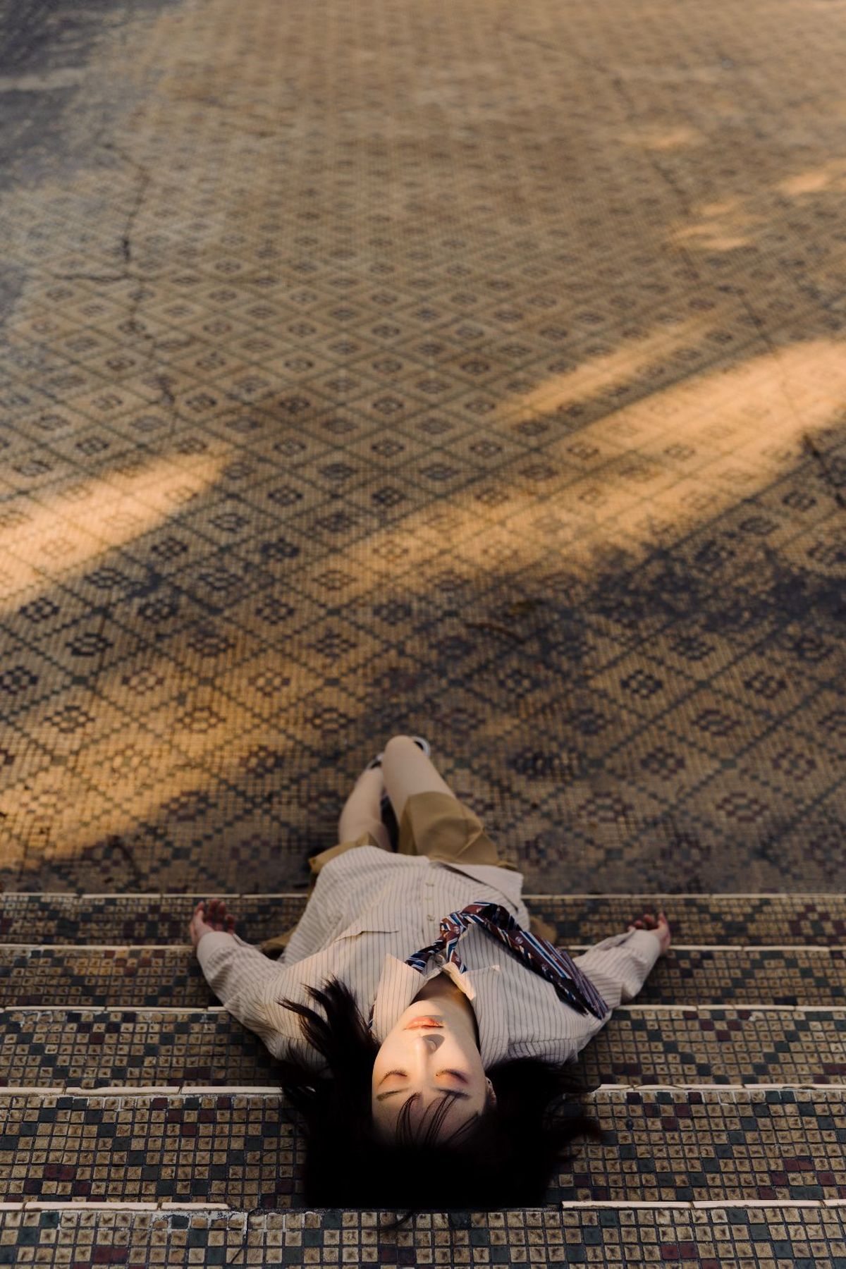一个年轻女子躺在人行道地板上 一个穿领带的男子躺在地上。
