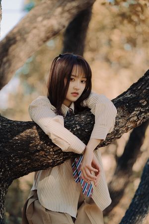 一位年轻女子在树下穿着毛衣