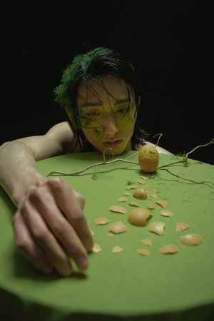 一个留着绿色头发的年轻女子正在用刀割自己的脸。