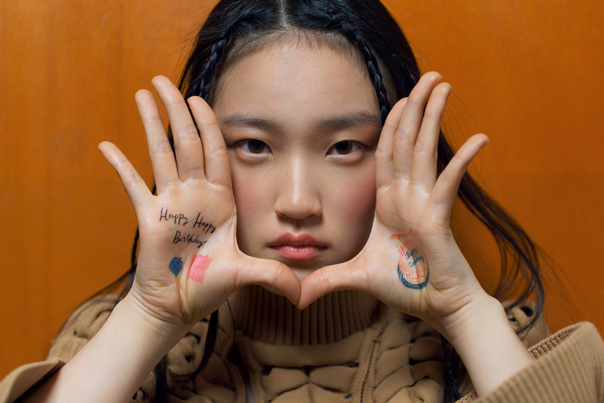 一个有手部纹身的年轻女子用手指遮住脸