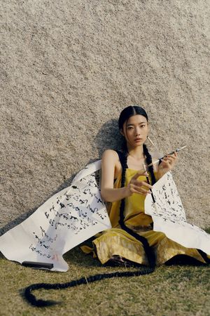 一位身着传统和服的年轻女子坐在混凝土墙边 吸着香烟 坐在地板上。