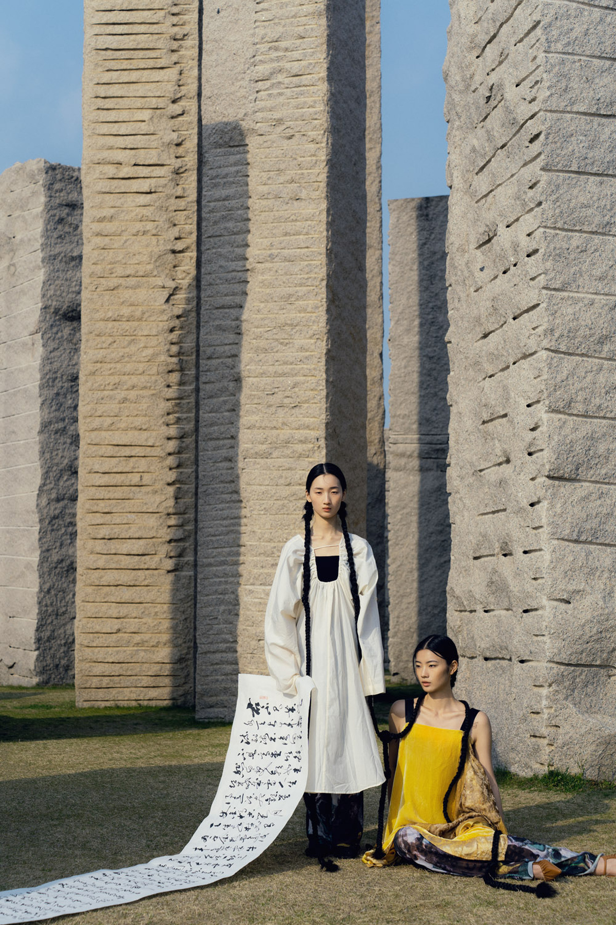 一位年轻女孩和一位妇女站在一个纪念碑前 背景墙上有图案。